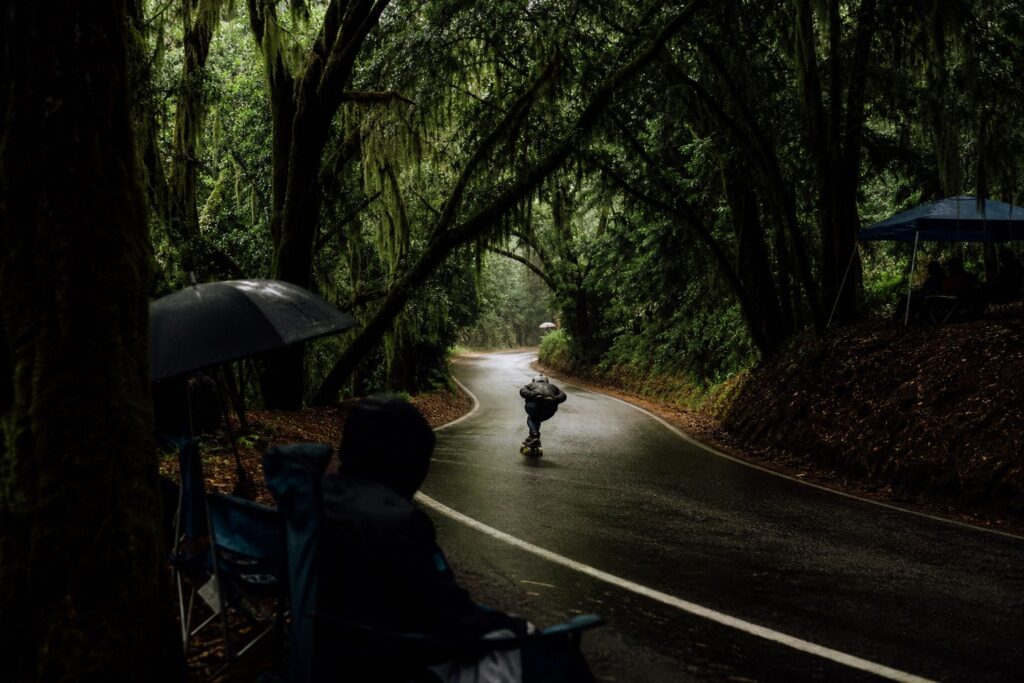 A downhill rider tucked along a humid southern road lined with moss-draped oaks